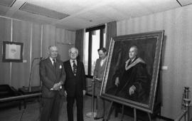 Photograph of Chester Stewart and two unidentified people with a painting
