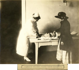 Photograph of Health Centre No. 1 nurse leaning over and measuring baby
