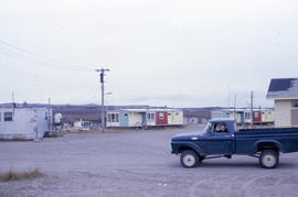 Photograph of a truck driving past some houses in northern Quebec
