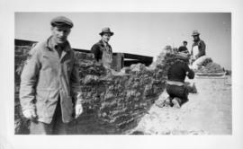 Photograph of men building a stone wall