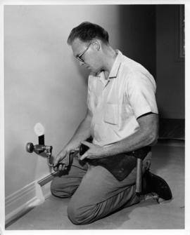 Photograph of an unidentified person installing a phone jack
