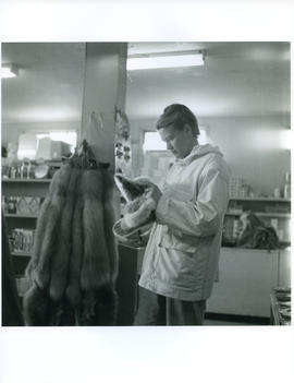 Photograph of Barbara Hinds looking at fur slippers in a store