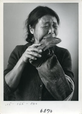 Photograph of a woman chewing sealskin boots in Cape Dorset, Northwest Territories
