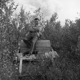 Photograph of an unidentified man sitting on an abandoned cart