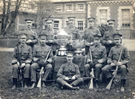 Portrait of the British Army shooting team with two trophies, in uniform and carrying rifles, tak...