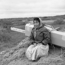 Photograph of a woman carrying pieces of a packing case with a harness in Fort Chimo, Quebec