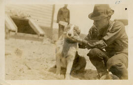 Photograph of a wireless operator and petting a dog outside the wireless station on Sable Island