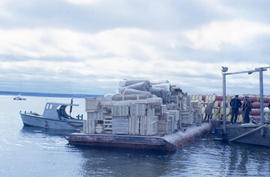 Photograph of a pile of wooden crates and packages on a barge