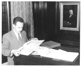 Photograph of a man looking at a book in the Kipling room at the Macdonald library