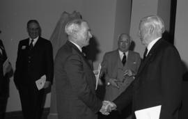 Photograph of Norman A. M. MacKenzie shaking hands with an unidentified person