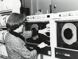 Photograph of a woman replacing a reel of magnetic tape