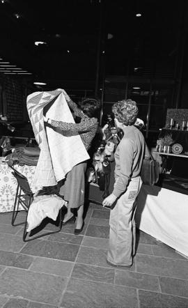 Photograph of two people looking at a quilt at a craft market