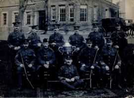 Portrait of the British Army shooting team with a trophy, in uniform and carrying rifles, taken a...
