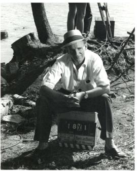 Photograph of chief cameraman Ernest Kirkpatrick sitting on a Film Production Toronto box near a ...