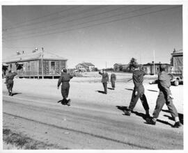 Photograph of four unidentified soldiers marching to church, saluted by Brigadier Roome and Major...