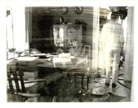 Photograph of a T.V. crewman standing in the doorway of Thomas Head Raddall's dining room looking...