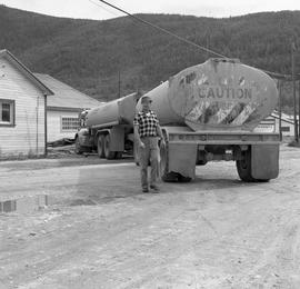 Photograph of an unidentified man standing by a fuel truck in Dawson City, Yukon