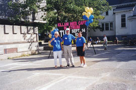 Photograph of Elaine Boychuk, Bill Maes and Jo-Ann Riggs in front of the outdoor signage for the ...