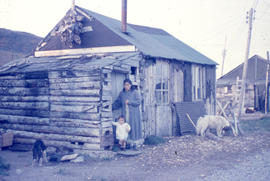 Photograph of a woman and baby standing by the door of a house in Nain, Newfoundland and Labrador