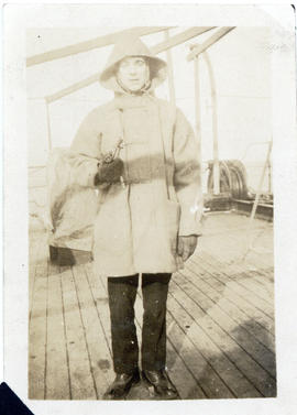 Photograph of chief electrician Cyril Taylor dressed for winter on the deck of the cable-ship Mac...