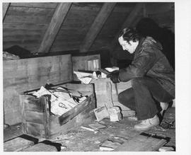 Photograph of Charles Armour looking at crates of documents