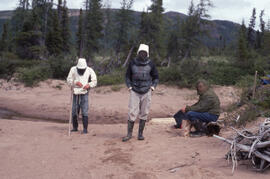 Photograph of three unidentified people wearing insect repellent clothing near Voisey's Bay, Newf...