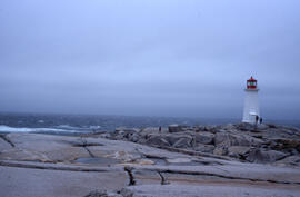 Wide-angle photograph of five unidentified persons standing on the rocks near Peggys Cove Lighthouse