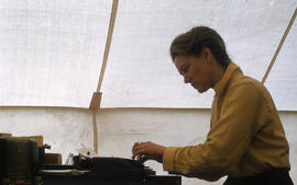 Photograph of Barbara Hinds typing in a tent in George River, Quebec