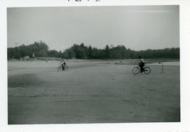 Photograph of two boys riding their bicycles on the exposed bottom of Lake Wentworth after an ext...