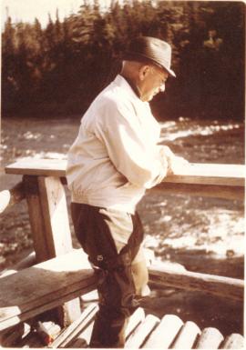 Photograph of a man watching the salmon run from the side of a deck
