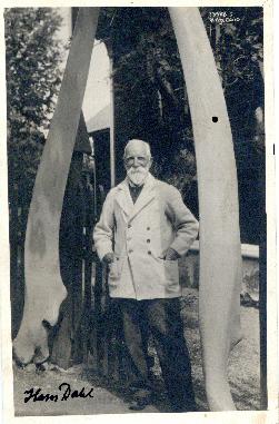 Photograph of Norwegian artist Hans Dahl standing between whale jawbones in Balestrand, Norway pr...
