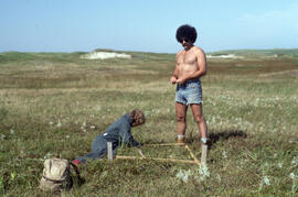 Photograph of Bill Freedman and one unidentified person building an enclosure on a grassy plain o...