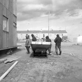 Photograph of four people with a cart at a construction site in Fort Chimo, Quebec
