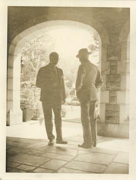Photograph of two unidentified people by an arch