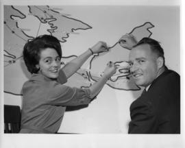 Photograph of an unidentified male and female by a map of the TransCanada Microwave System
