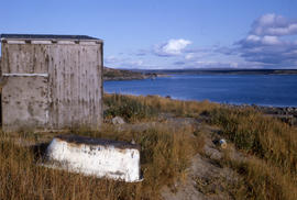 Photograph of a shed on a grassy hill near the shore in northern Quebec