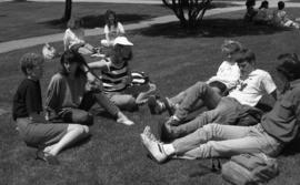 Photograph of students sitting on the lawn in front of the Henry Hicks Building
