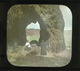 Photograph of two women in front of rock arch along the Bay of Fundy