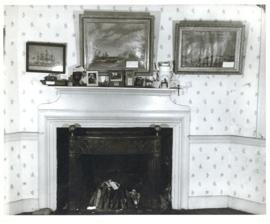 Photograph of a mantel in the Simeon Perkins house before its restoration, with several framed ph...