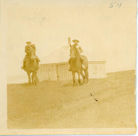 Photograph of two unidentified people on horseback in front of the refuge house near the eastern ...