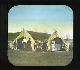 Photograph of a family standing in front of two tents