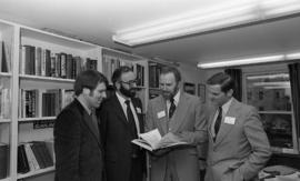 Photograph of four unidentified people looking at a book together