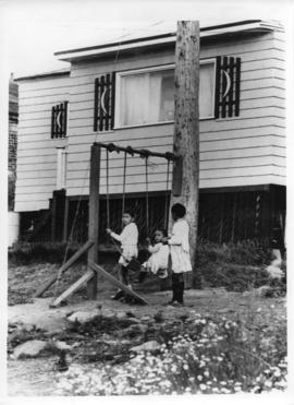 Photograph of children playing on swings in Africville