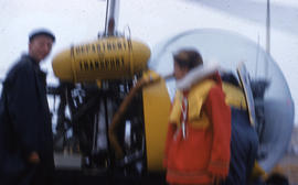 Photograph of two people standing with a helicopter