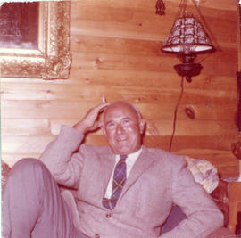 Photograph of Thomas Head Raddall sitting in a den with a cigarette
