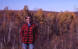 Photograph of Tom Hutchinson standing amid a birch stand, near Sudbury, Ontario