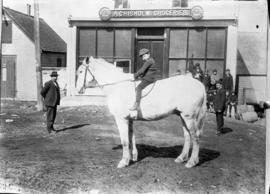 Photograph of a boy on a horse in front of the A. Chisholm Groceries store