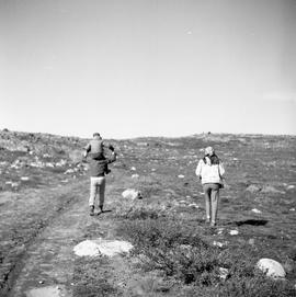 Photograph of a man, a woman, and a child walking across the tundra in Northern Quebec