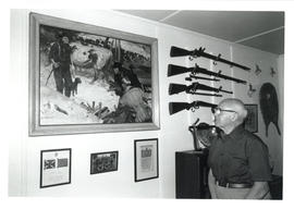 Photograph of Thomas Head Raddall in his study looking at a painting by John Clymer of "Scabby Lo...