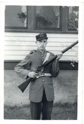 Photograph of Arthur White holding a rifle and dressed in period uniform as a private for the Nov...